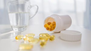 healthy-lifestyle-medicine-nutritional-supplements-people-concept-close-up-male-hands-holding-pills-with-cod-liver-oil-capsules-water-glass